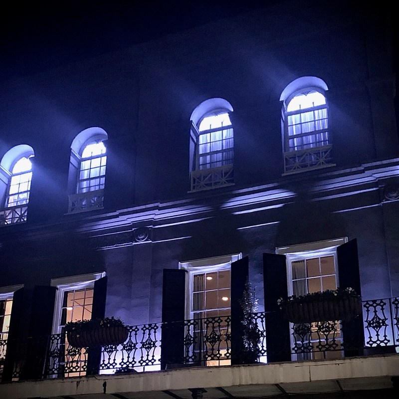 Illuminated building facade with arched windows and balconies at night.
